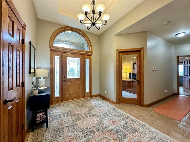 entryway featuring plenty of natural light, baseboards, and a notable chandelier