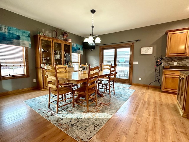 dining space featuring light wood-style flooring, baseboards, and an inviting chandelier