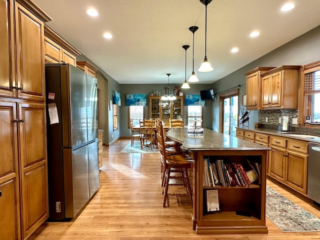 kitchen featuring light wood-style flooring, backsplash, a center island, stainless steel appliances, and a sink