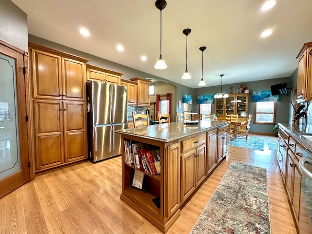 kitchen with brown cabinets, freestanding refrigerator, a center island, open shelves, and dark stone countertops