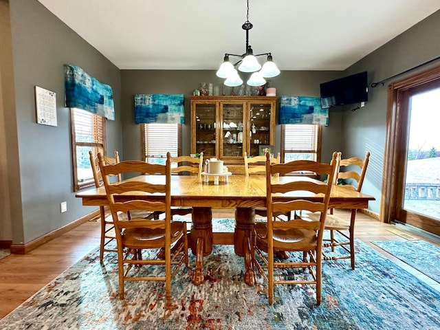 dining space with light wood-style floors, baseboards, and an inviting chandelier