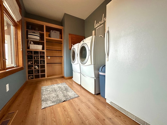 washroom featuring laundry area, wood finished floors, washing machine and clothes dryer, and visible vents