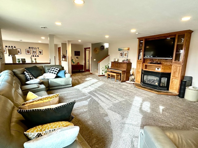 living area with recessed lighting, a glass covered fireplace, and carpet