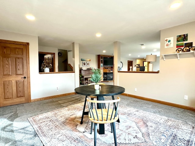 carpeted dining room with recessed lighting, baseboards, and a glass covered fireplace