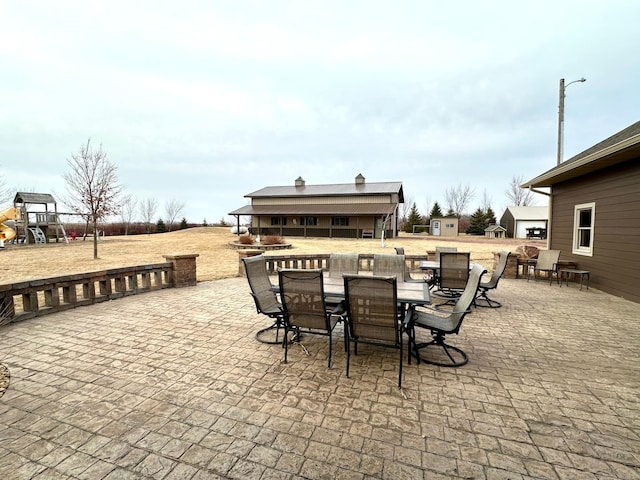 view of patio / terrace with an outbuilding, outdoor dining area, and a playground