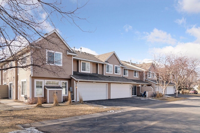 multi unit property featuring a garage, a residential view, driveway, and a shingled roof