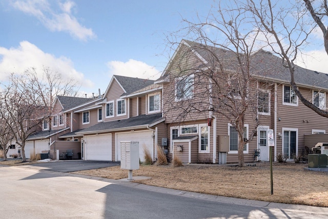 multi unit property with aphalt driveway, an attached garage, a residential view, and a shingled roof