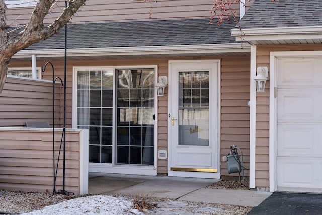 property entrance with a shingled roof and an attached garage