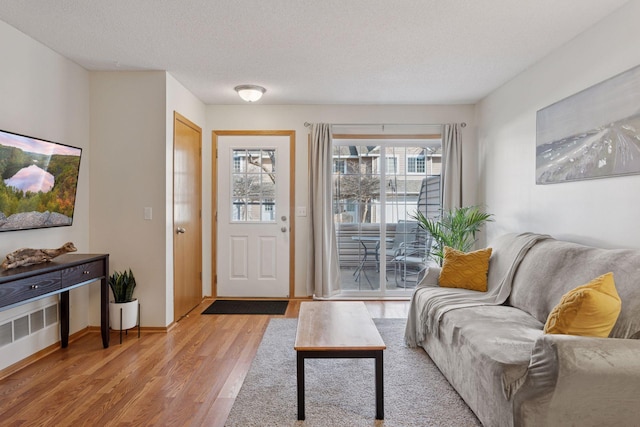 interior space with light wood finished floors, baseboards, and a textured ceiling