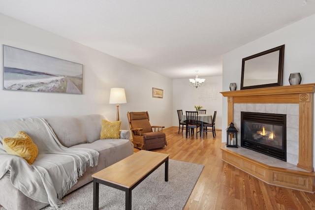 living area featuring a fireplace, light wood-style flooring, and an inviting chandelier