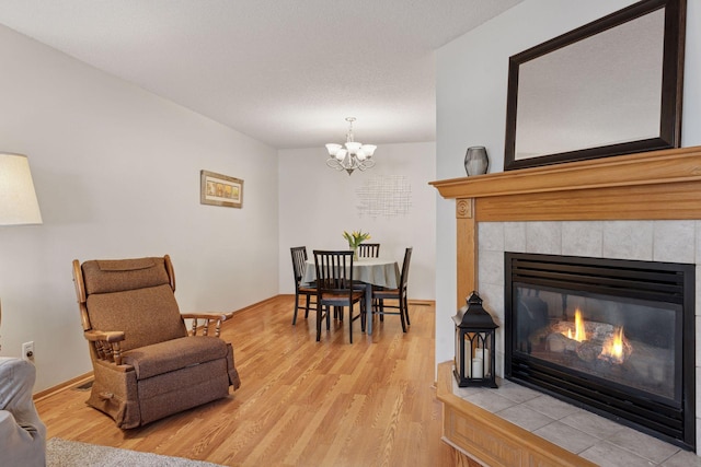 interior space with light wood-style floors, a tiled fireplace, and an inviting chandelier