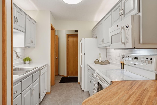 kitchen with white appliances, light countertops, a sink, and light tile patterned flooring