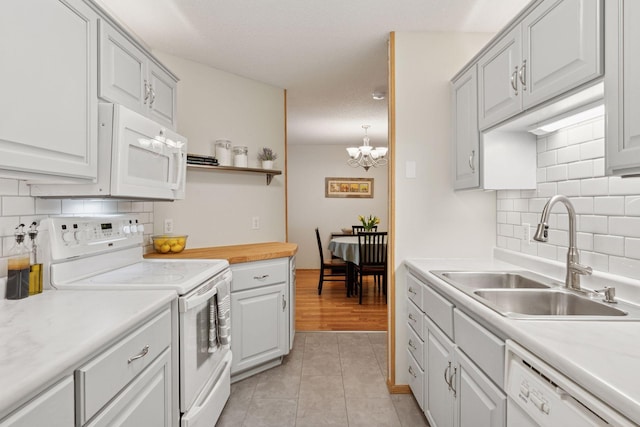 kitchen featuring light tile patterned floors, white appliances, backsplash, and a sink