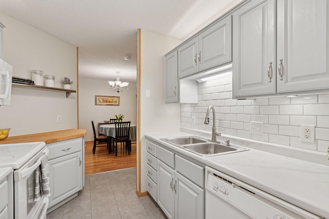 kitchen featuring light tile patterned floors, tasteful backsplash, light countertops, a sink, and white appliances