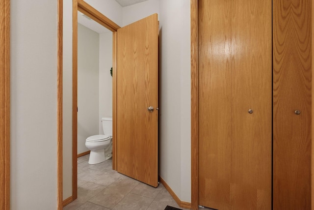 corridor with light tile patterned flooring and baseboards