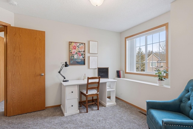 carpeted office space with a textured ceiling and baseboards