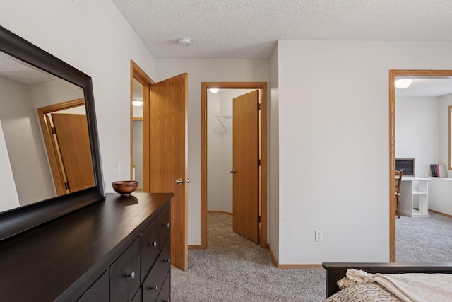 bedroom with light carpet, a textured ceiling, and baseboards