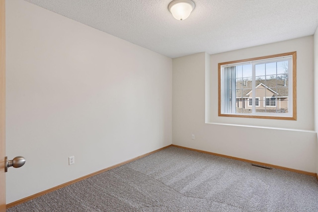 carpeted empty room featuring a textured ceiling, visible vents, and baseboards