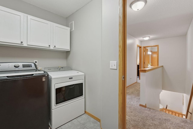 clothes washing area with cabinet space, visible vents, a textured ceiling, washer and dryer, and baseboards