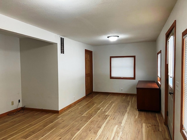 empty room with light hardwood / wood-style flooring and a textured ceiling