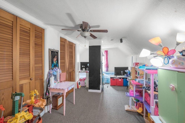 rec room with dark colored carpet, lofted ceiling, ceiling fan, and a textured ceiling