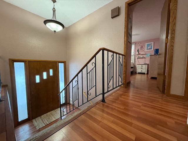 entrance foyer featuring stairs, a textured wall, and wood finished floors