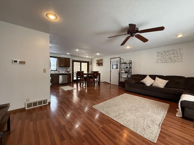 living area featuring a textured ceiling, dark wood-style flooring, and visible vents