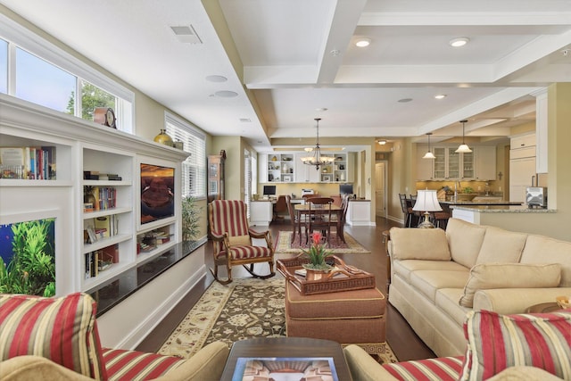 living area with a chandelier, wood finished floors, visible vents, baseboards, and beamed ceiling