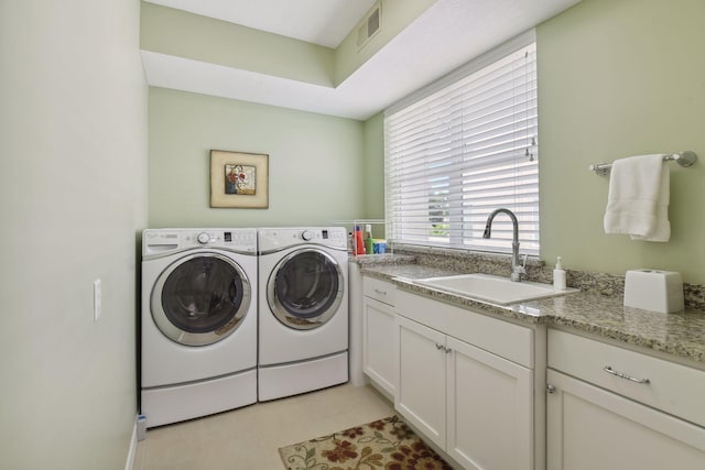 washroom featuring washing machine and dryer, visible vents, a sink, and cabinet space