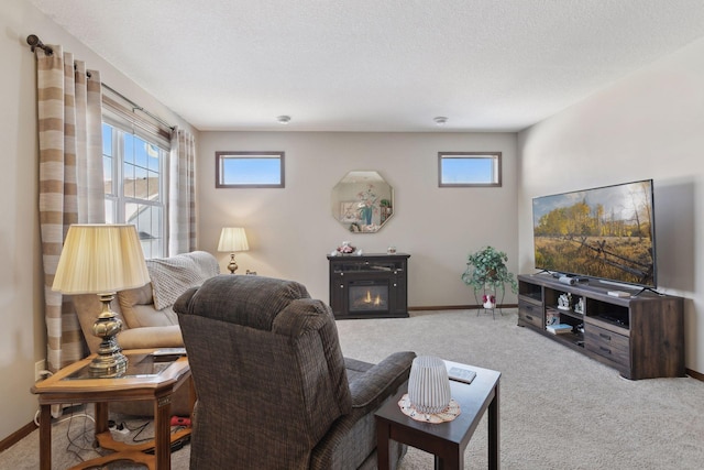 living area with baseboards, a glass covered fireplace, and light colored carpet