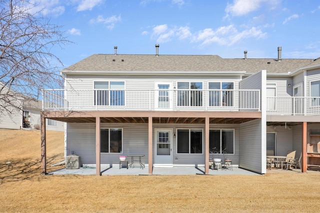 back of house featuring a patio, a lawn, and roof with shingles