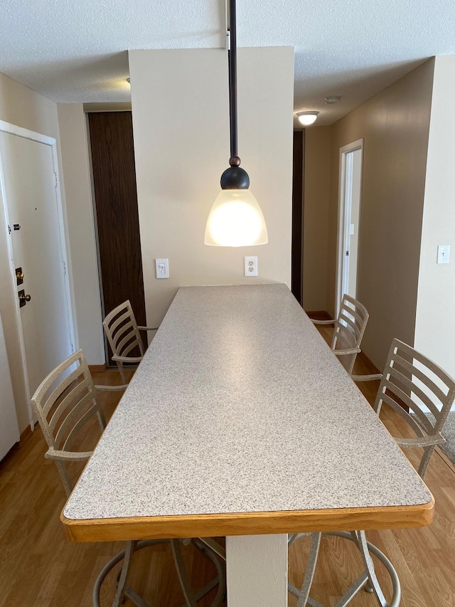 kitchen with hardwood / wood-style flooring, a textured ceiling, and kitchen peninsula