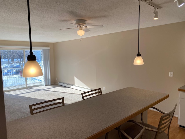 unfurnished dining area featuring a baseboard radiator, rail lighting, carpet flooring, ceiling fan, and a textured ceiling