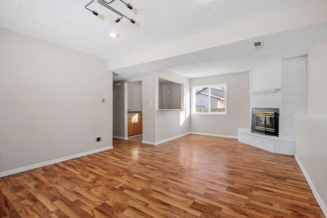 unfurnished living room with a fireplace, wood-type flooring, and a textured ceiling