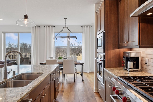 kitchen with appliances with stainless steel finishes, plenty of natural light, a sink, and under cabinet range hood