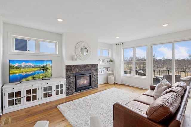 living area with a healthy amount of sunlight, a fireplace, wood finished floors, and recessed lighting