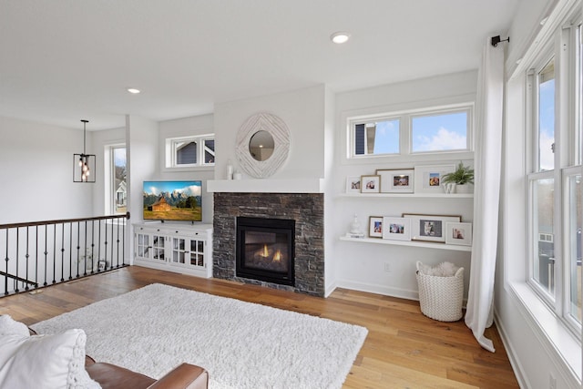 living area featuring a fireplace, wood finished floors, a wealth of natural light, and baseboards