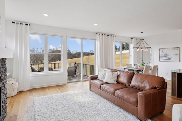 living area with recessed lighting, an inviting chandelier, light wood-style flooring, and baseboards