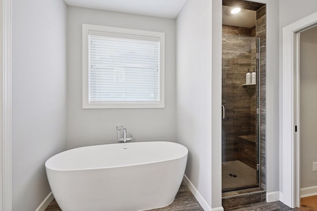 full bathroom featuring a freestanding bath, wood finished floors, a shower stall, and baseboards