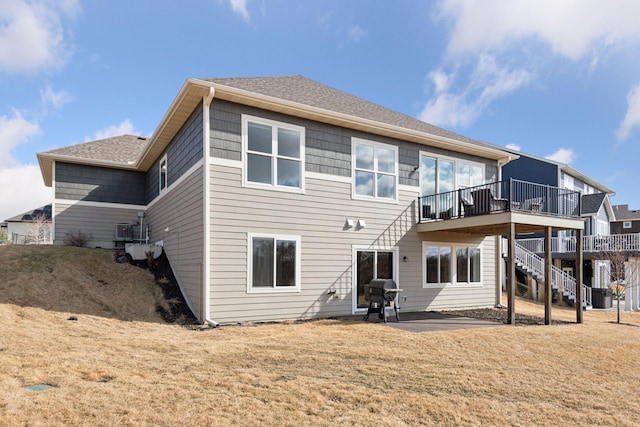 back of property featuring a shingled roof, a lawn, stairway, and a wooden deck