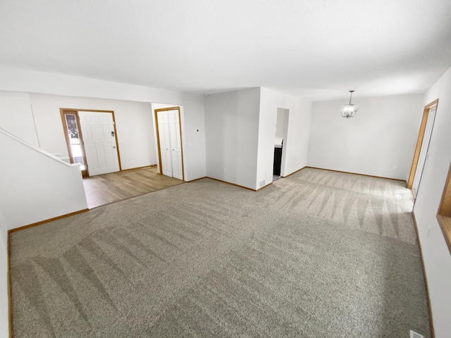 unfurnished living room with carpet and a notable chandelier