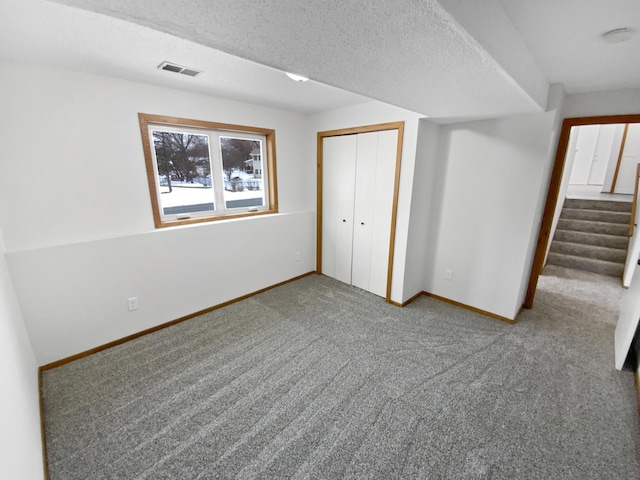 unfurnished bedroom featuring carpet flooring, a textured ceiling, and a closet