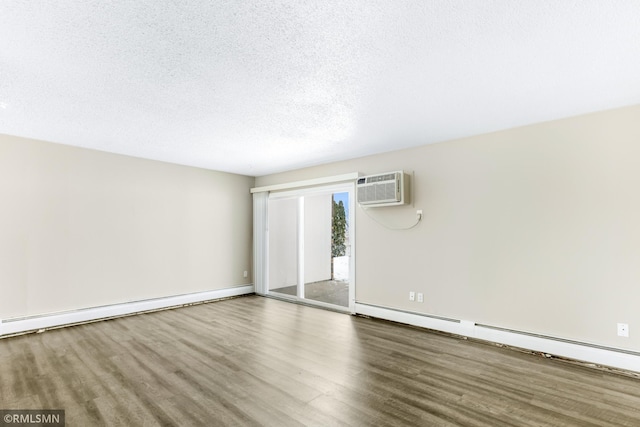 empty room featuring baseboard heating, wood-type flooring, a wall unit AC, and a textured ceiling