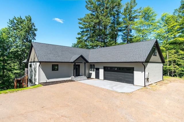 view of front facade with a shingled roof, an attached garage, and dirt driveway