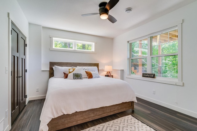 bedroom with dark wood-style floors, ceiling fan, multiple windows, and baseboards