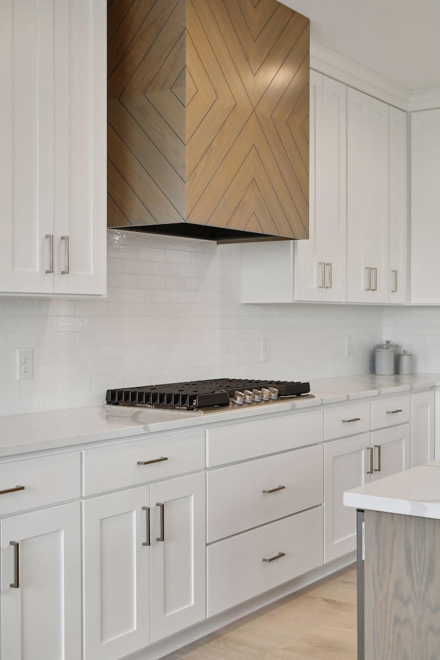 kitchen with custom exhaust hood, backsplash, white cabinetry, and light countertops