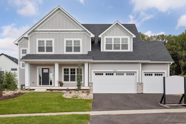 view of front facade with aphalt driveway, board and batten siding, a front yard, a shingled roof, and a garage