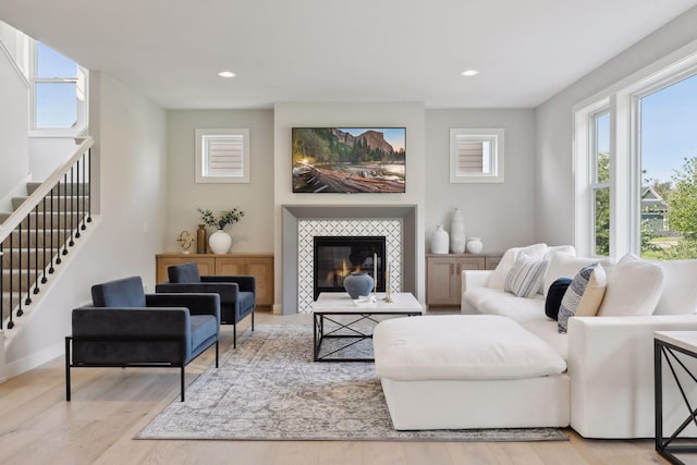 living area featuring wood finished floors, recessed lighting, stairway, baseboards, and a tile fireplace