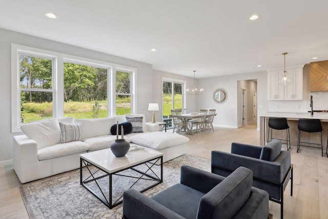 living room with light wood finished floors, recessed lighting, baseboards, and an inviting chandelier