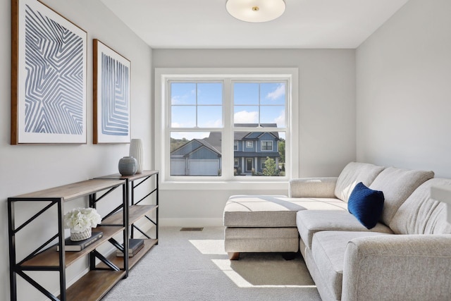 living area with baseboards, visible vents, and carpet floors